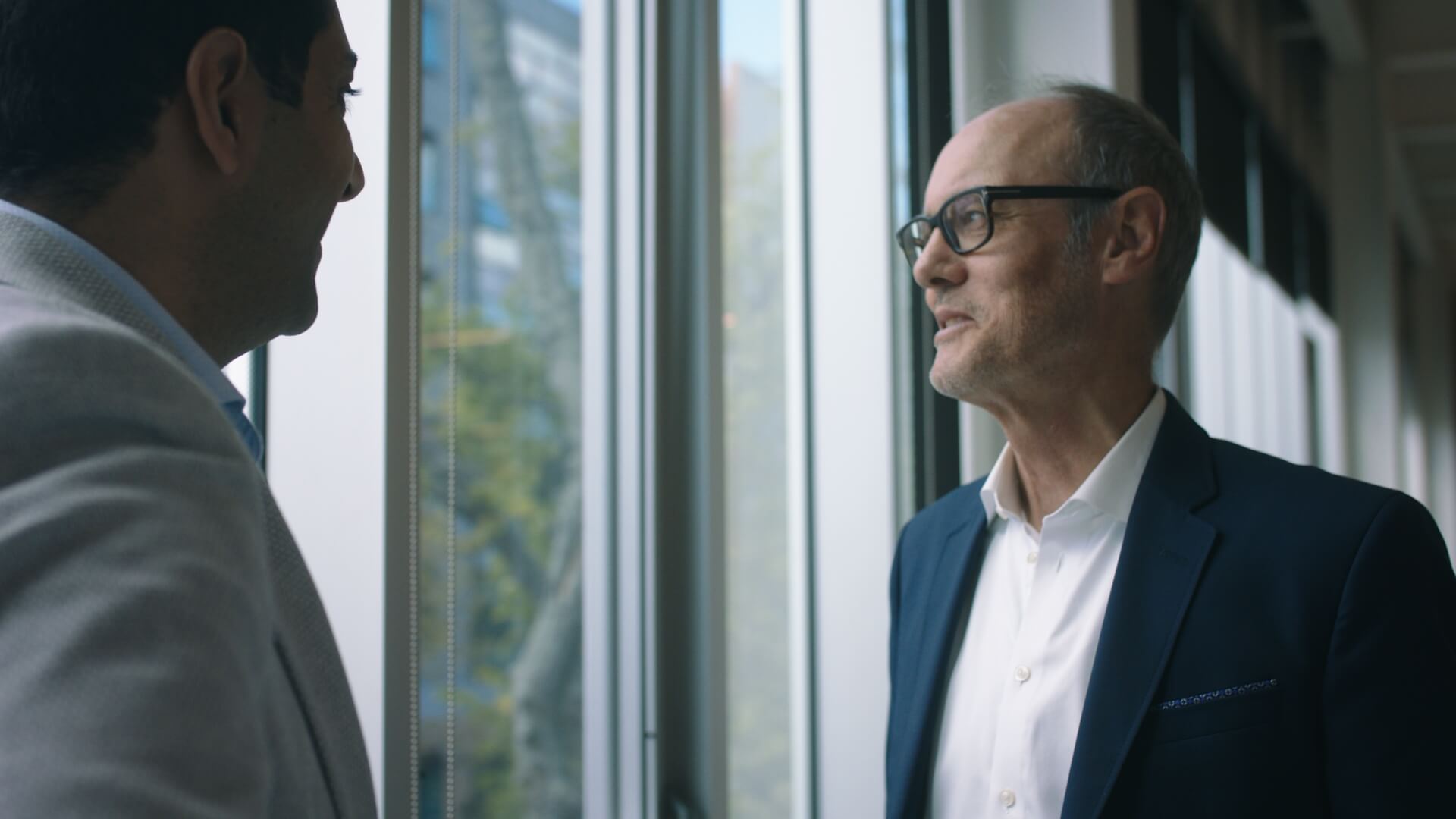 Two men talking by an office window in a documentary scene
