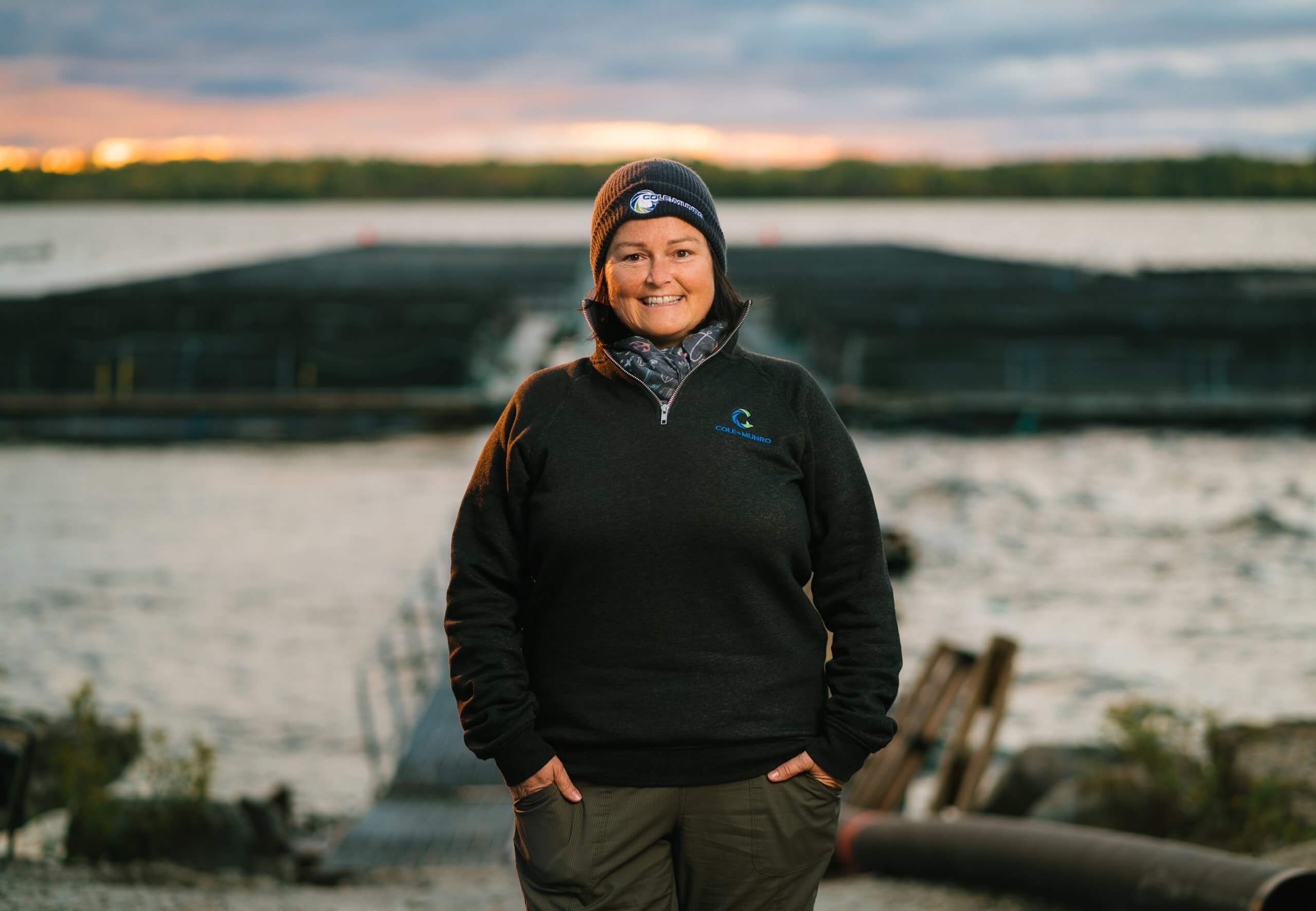 Portrait of a woman in a toque at a lakeside fish farm