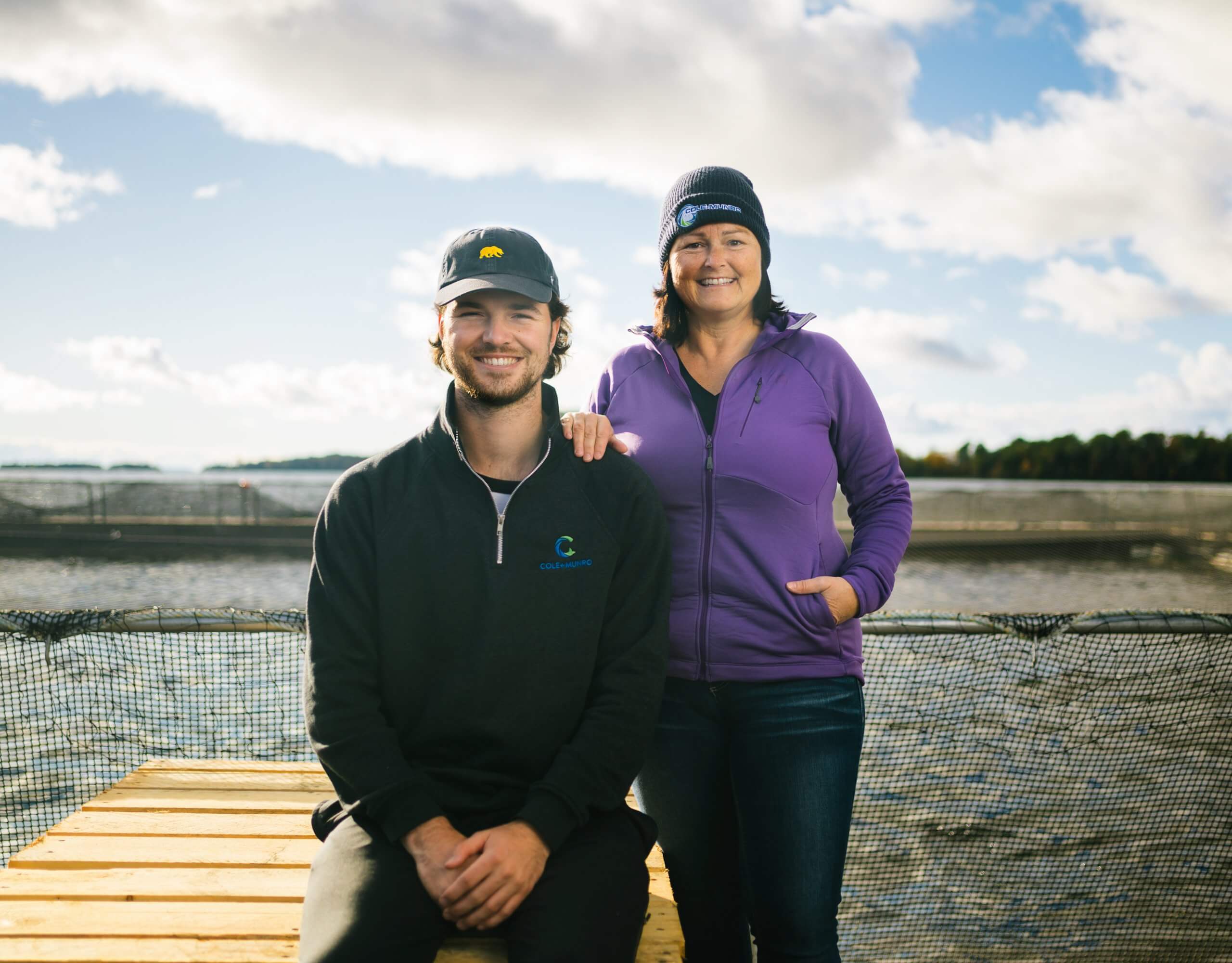 Two staff members standing on a fish farm dock