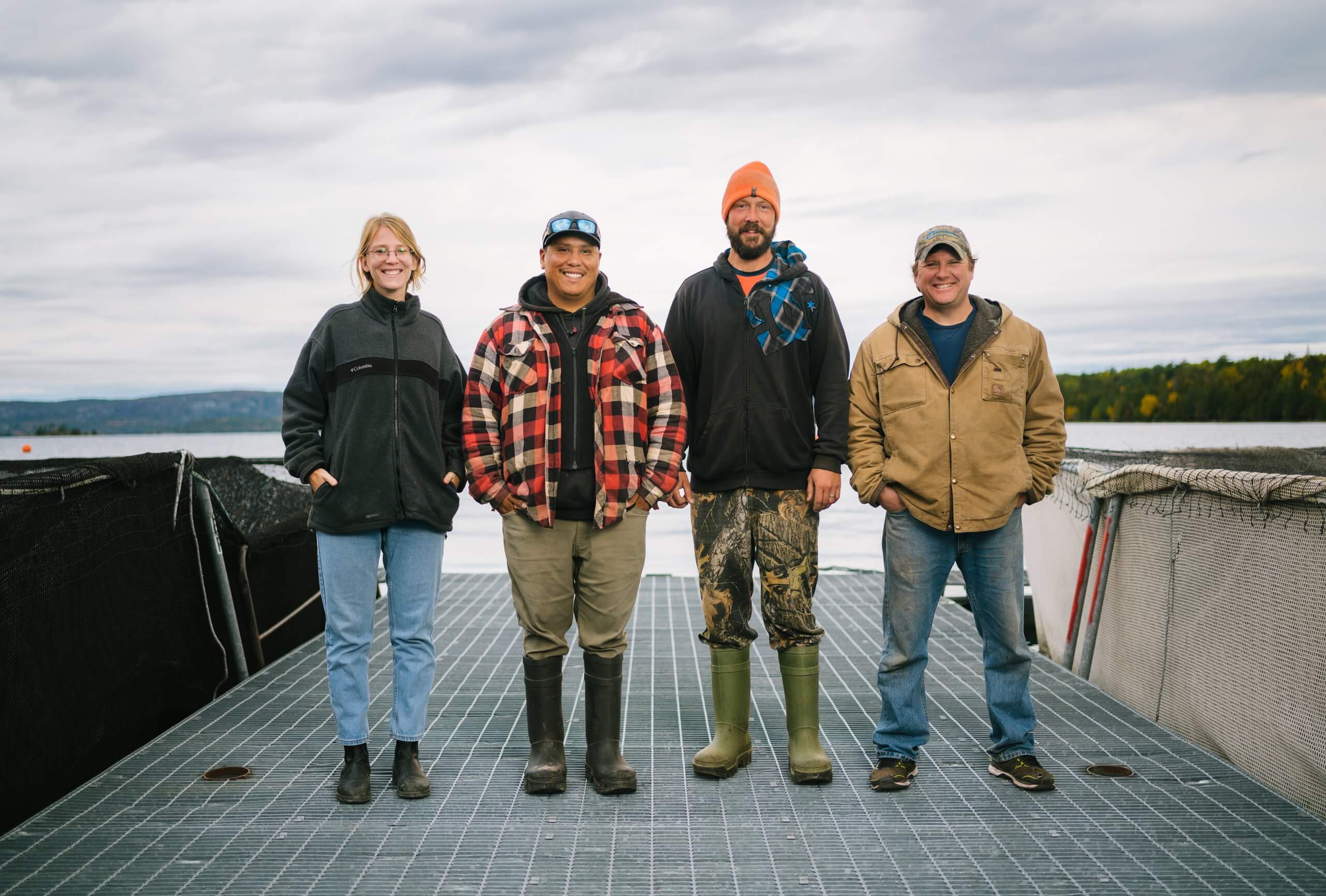 Four people standing on a dock by the water