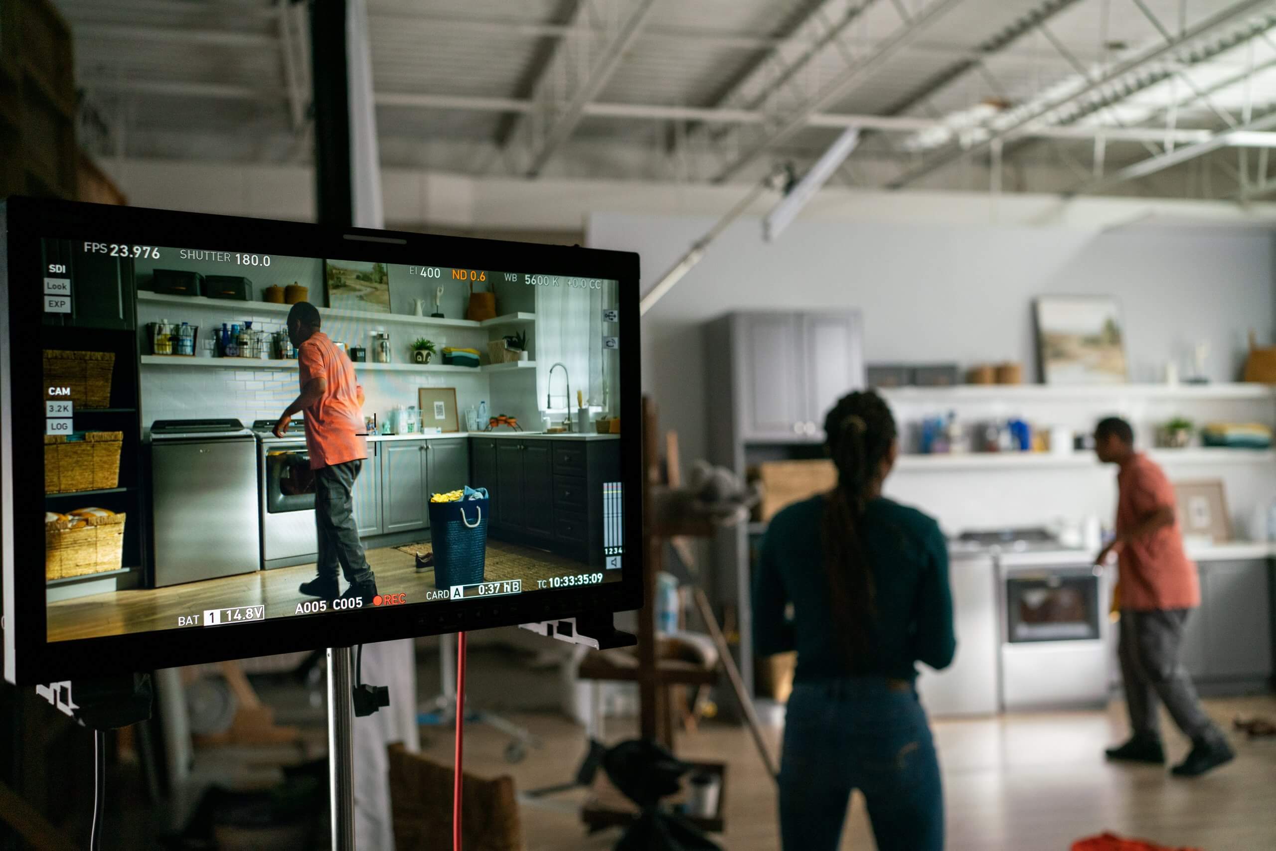 Crew filming a kitchen scene, seen on a set monitor