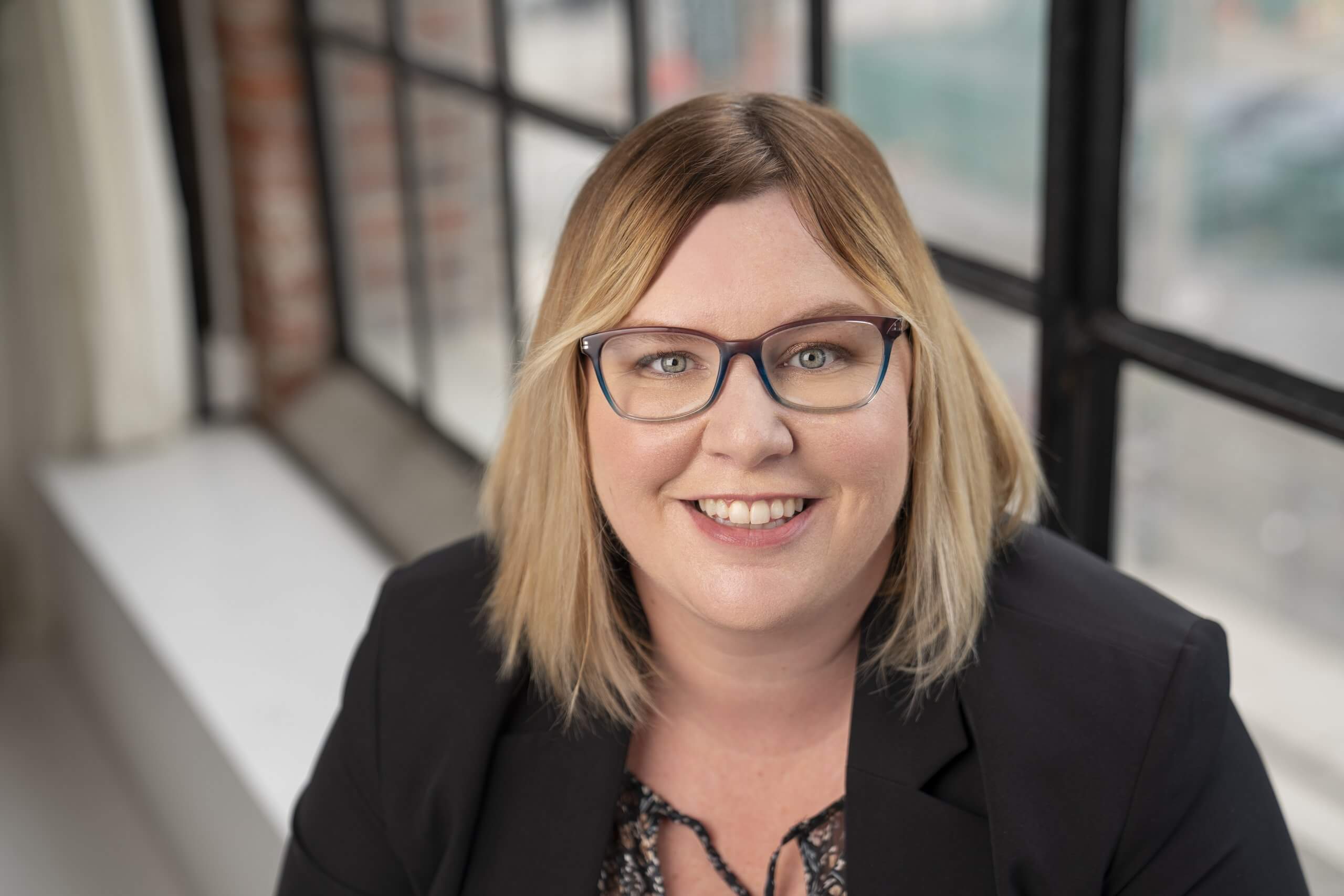 Corporate headshot of a smiling woman in glasses